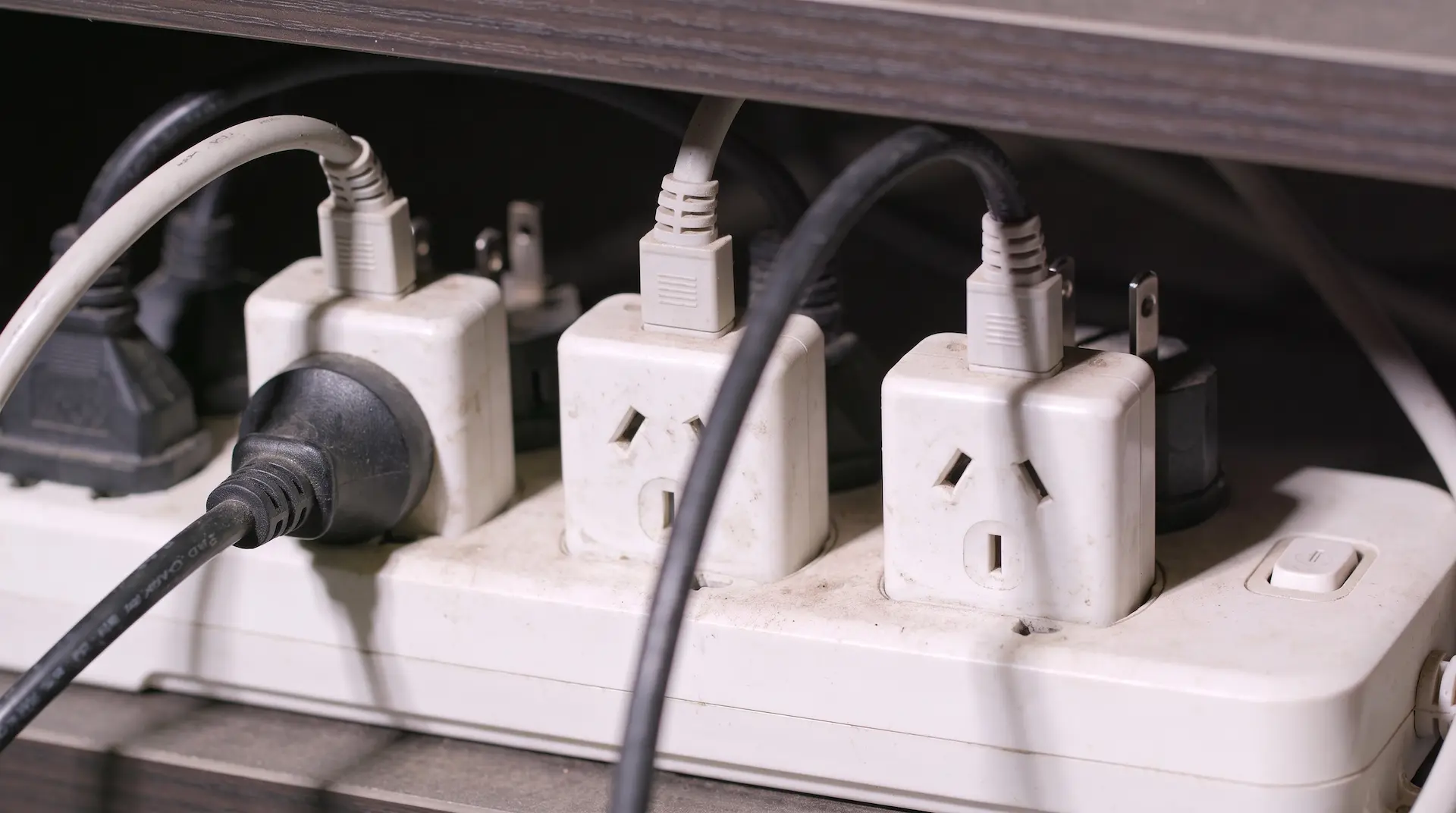 An overloaded power strip with too many plugs plugged in, a common electrical fire hazard in homes and workplaces.